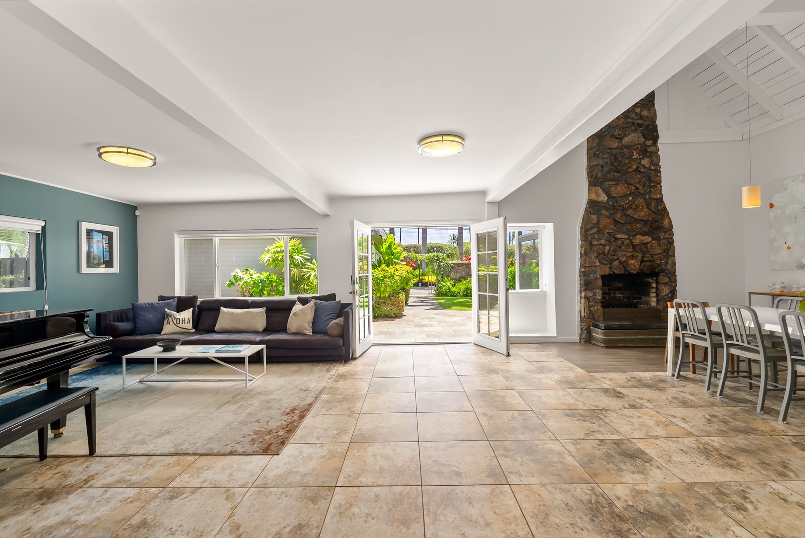 Honolulu Vacation Rentals, Ho'okipa Villa - Step into your sunlit sanctuary where modern comfort meets natural beauty. French doors frame lush garden views, inviting the outdoors in as you unwind by the striking stone fireplace.