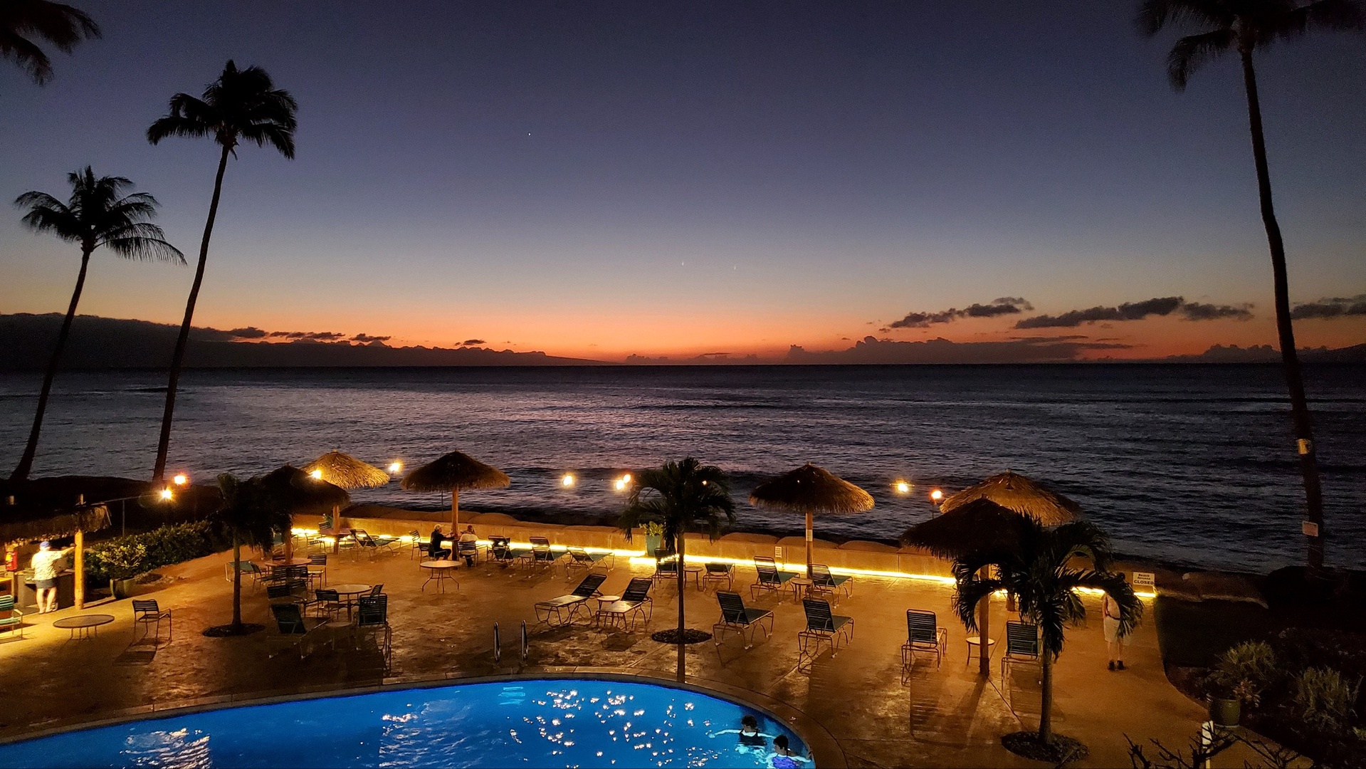 Lahaina Vacation Rentals, Royal Kahana 308 - This image showcases a serene beachfront pool area at dusk, with soft lighting illuminating the poolside