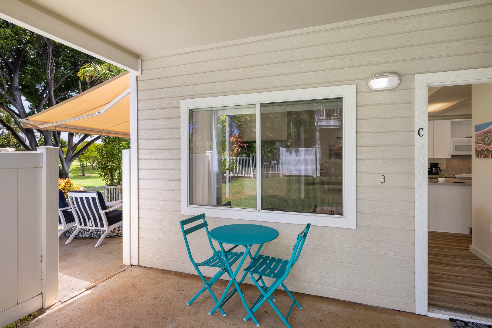 Your private patio features a charming turquoise bistro set where you can enjoy morning coffee with garden views through the large window.