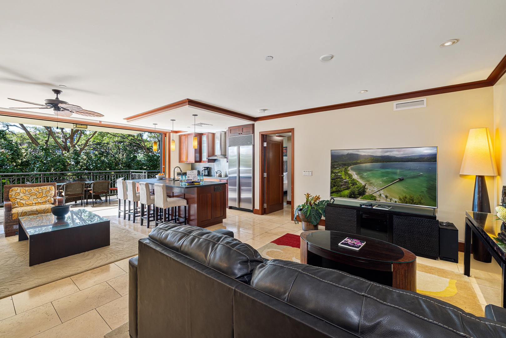 Unwind in your open-concept living space where lush tropical views and a modern kitchen blend seamlessly. Sink into the plush leather sofa and enjoy the natural light pouring in.
