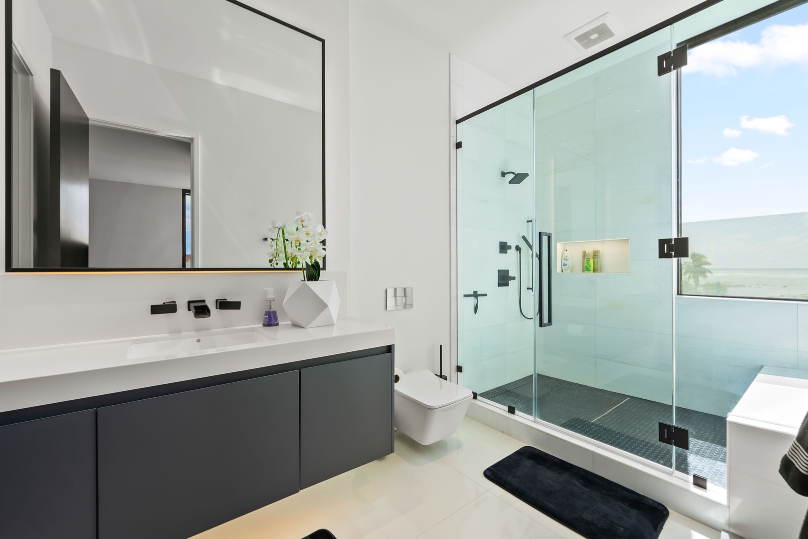 Honolulu Vacation Rentals, Ocean Villa Emilie - Bright white finishes and frameless glass define this sleek bath, ideal for refreshing before heading out to Waikiki or Sandy Beach.