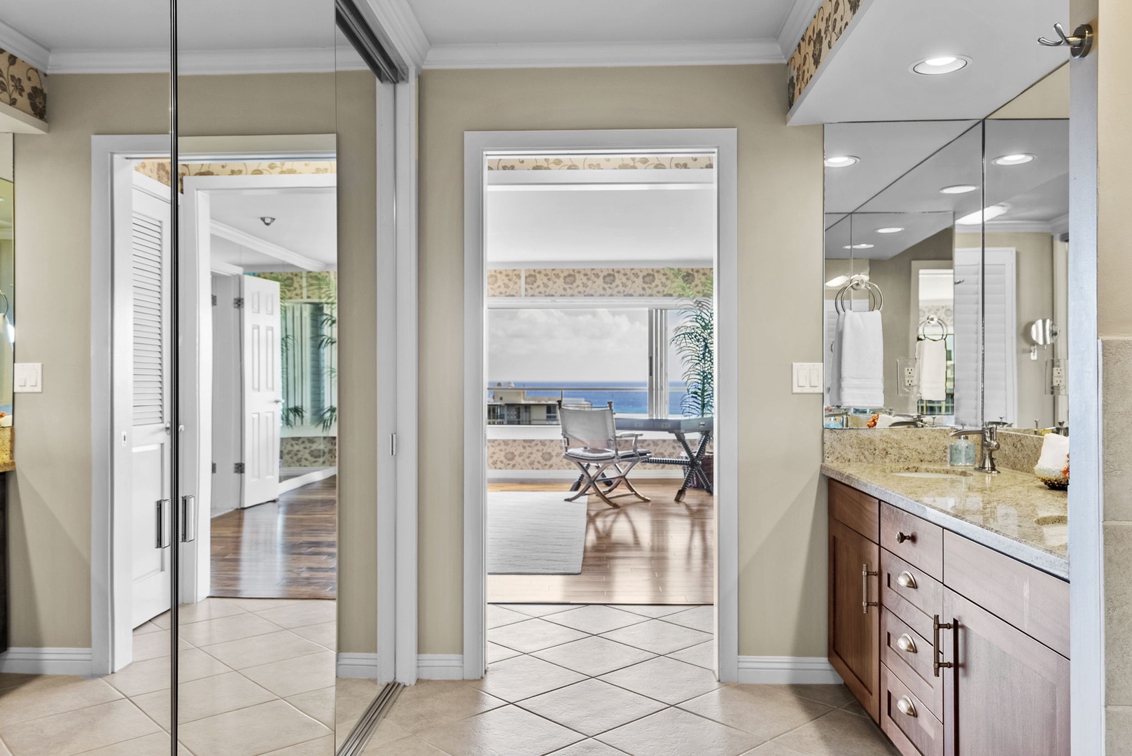 Honolulu Vacation Rentals, Hale Kaimana Breeze - A mirrored entryway leading to a spacious bathroom with granite countertops and ocean views in the background.