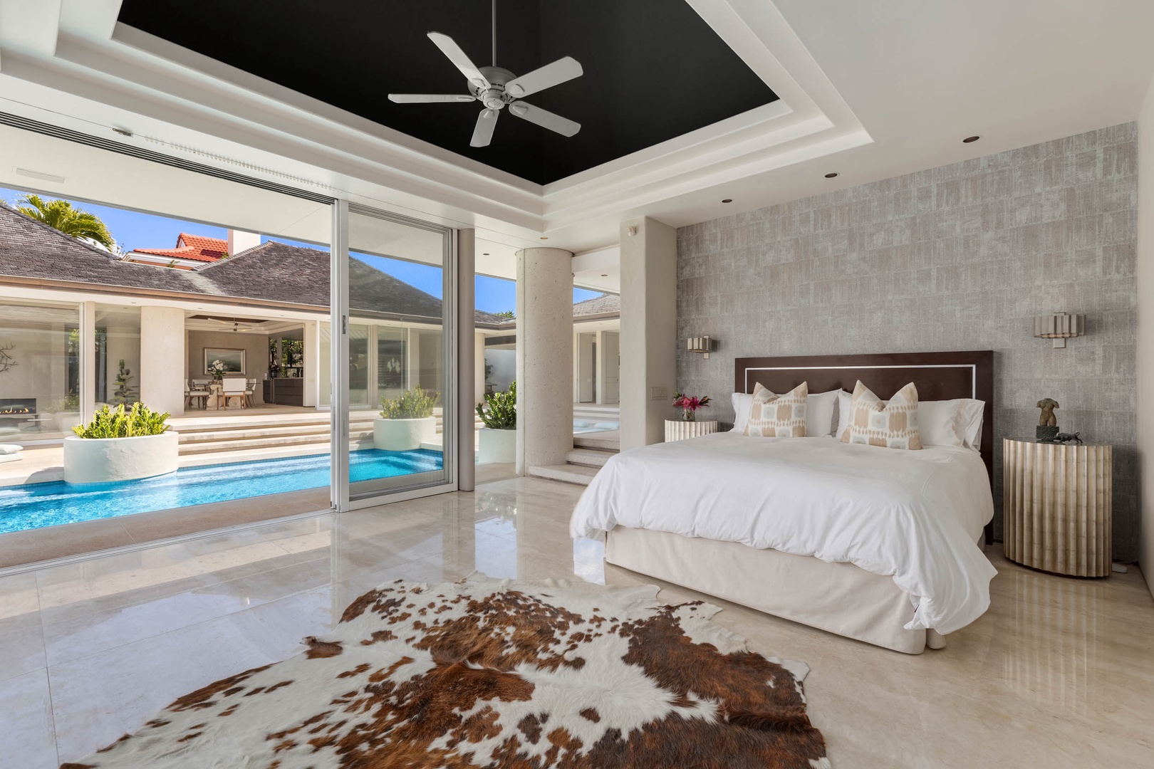 Honolulu Vacation Rentals, Sky Ridge House - Indulge in serene mornings in the grand primary suite, waking up to the gentle whir of a modern ceiling fan, nestled in a spacious bedroom with a plush king bed that seamlessly blends with an outdoor pool area.