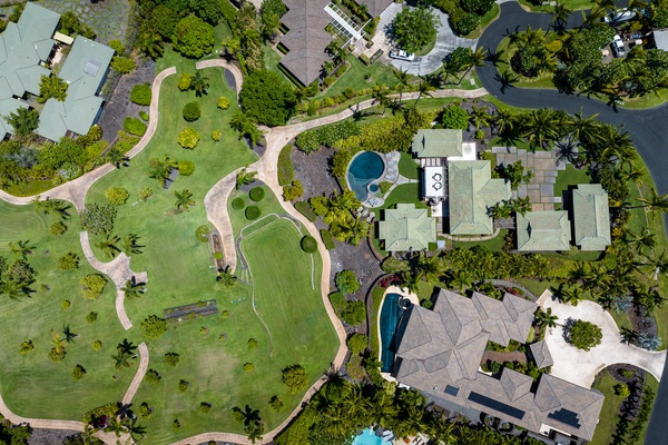 Kamuela Vacation Rentals, Canoe House & Beach Walker at Champion Ridge - A lush, green landscape with winding pathways surrounded by tropical trees and nearby homes.