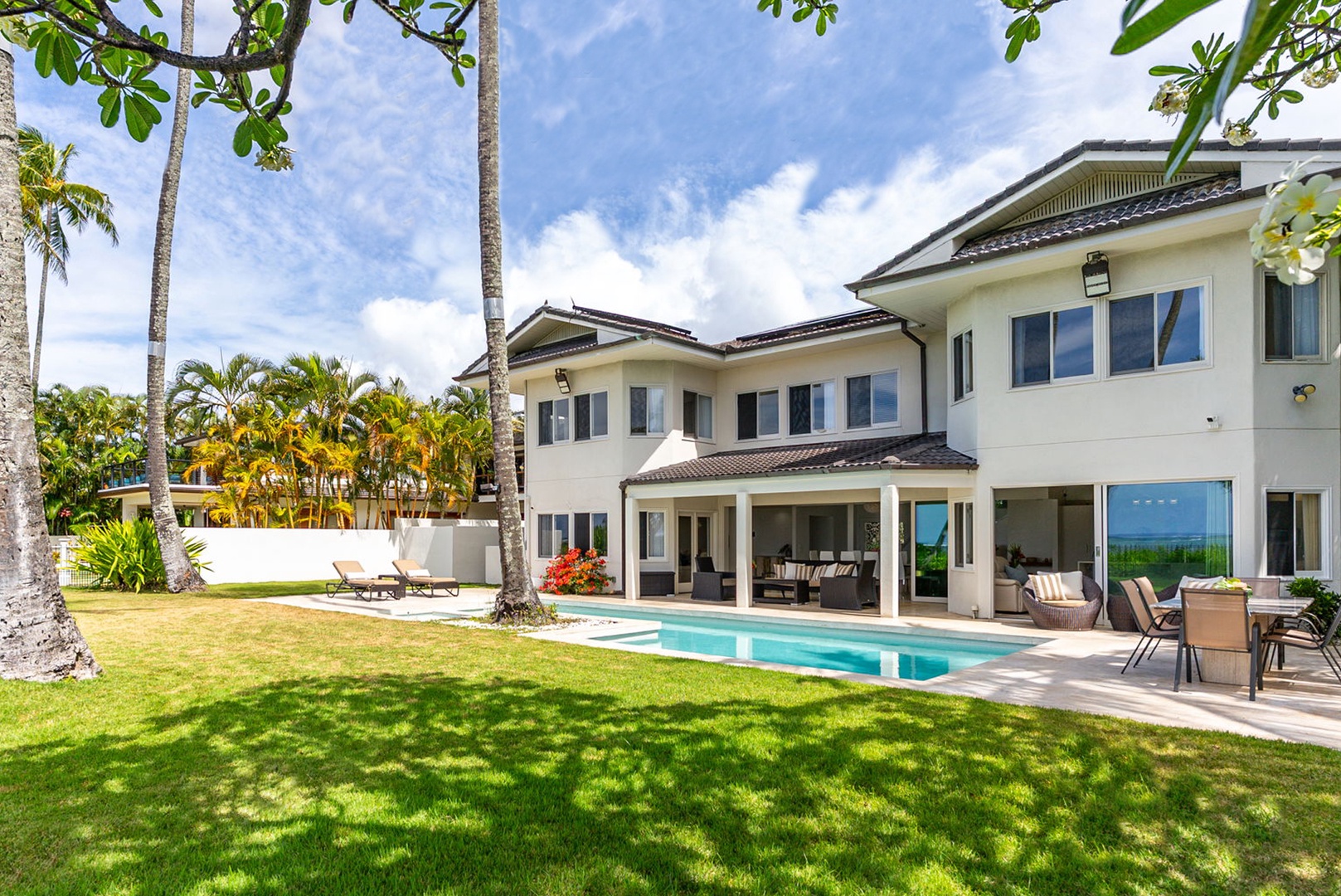 Honolulu Vacation Rentals, Paradise Beach Estate - Framed by swaying palms and Pacific views, the estate’s expansive beachfront lawn and pool set a tone of relaxed luxury from the moment you arrive.