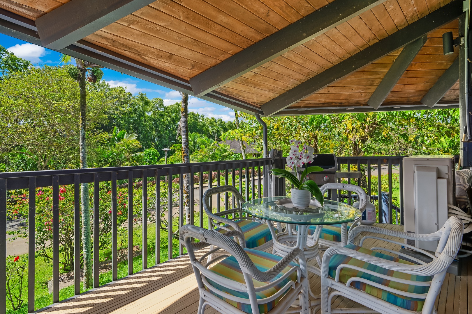 Princeville Vacation Rentals, Mauna Kai 7B - Breakfast under the open-beam ceiling, greenery close enough to reach through the railing.