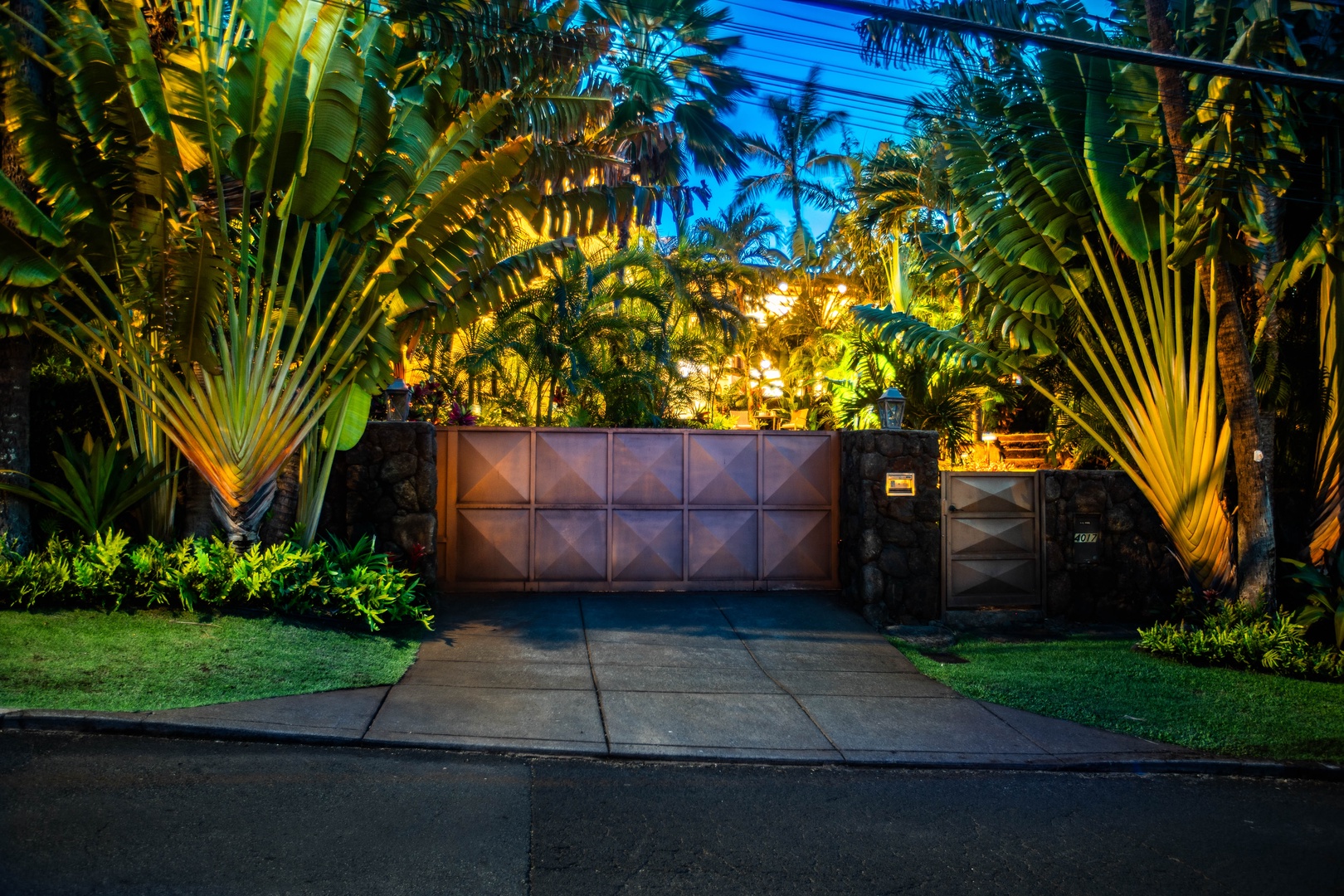 Honolulu Vacation Rentals, Pili Pono - Private gated entrance surrounded by lush palms and lights.
