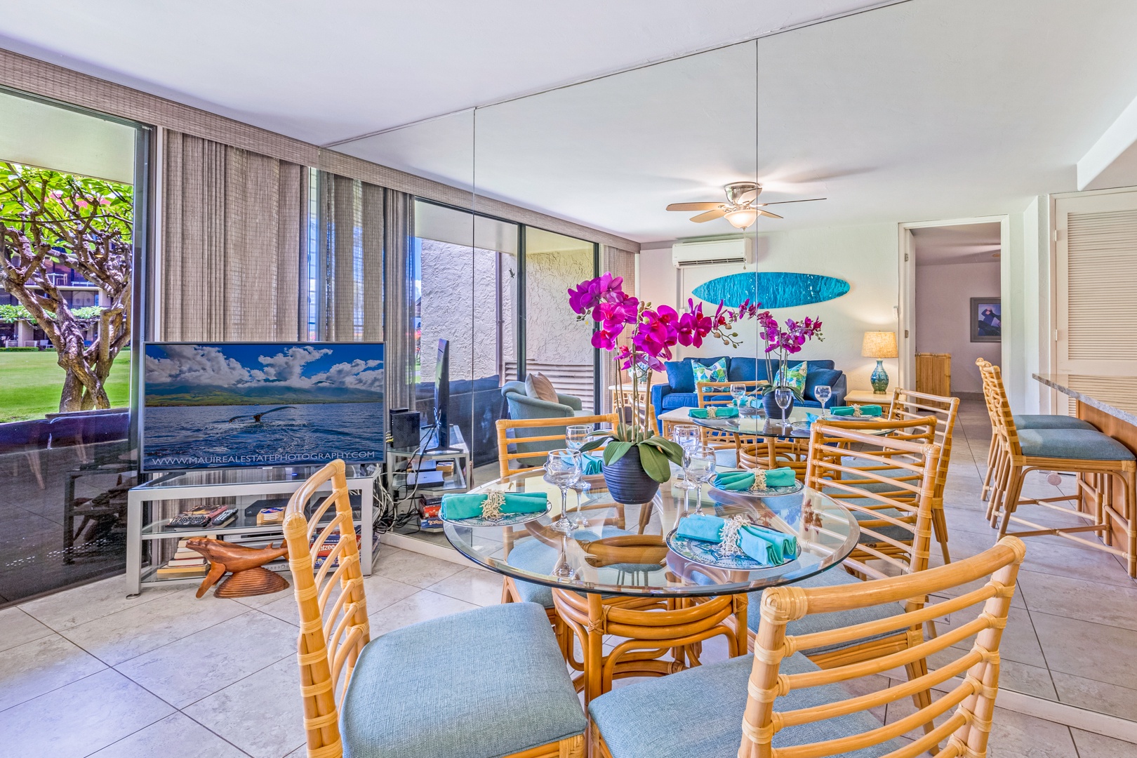 Lahaina Vacation Rentals, Papakea K-105 - The dining area, with its elegant glass table and tropical decor, is perfect for enjoying meals together while surrounded by natural light and garden views.