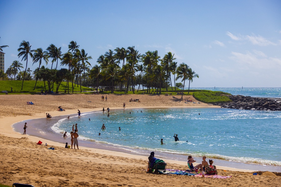 A stunning beach with golden sand, crystal-clear turquoise water, and swaying palm trees nearby. A popular gathering spot for families and beachgoers seeking sunshine and ocean views.