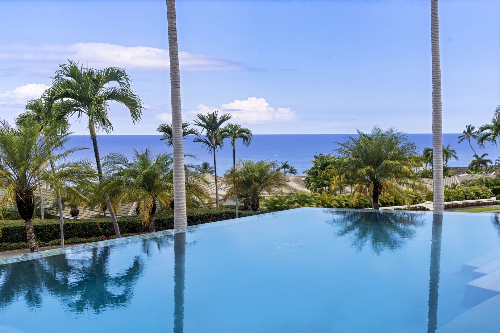 Kailua Kona Vacation Rentals, Kona Koa House - Infinity pool reflects ocean blues and swaying palms for the ultimate Big Island experience.