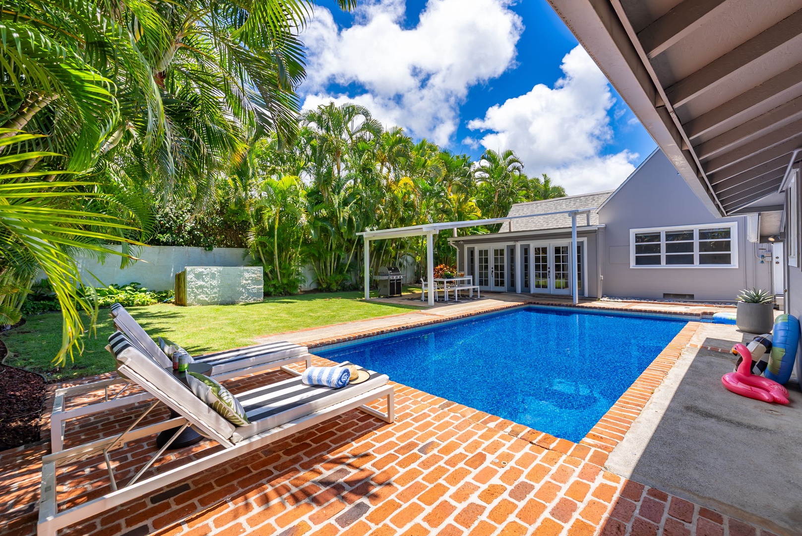 Honolulu Vacation Rentals, Ho'okipa Villa - Step onto your private patio where a sparkling pool awaits, framed by lush palms and manicured lawn—your tropical retreat for sun-soaked relaxation.