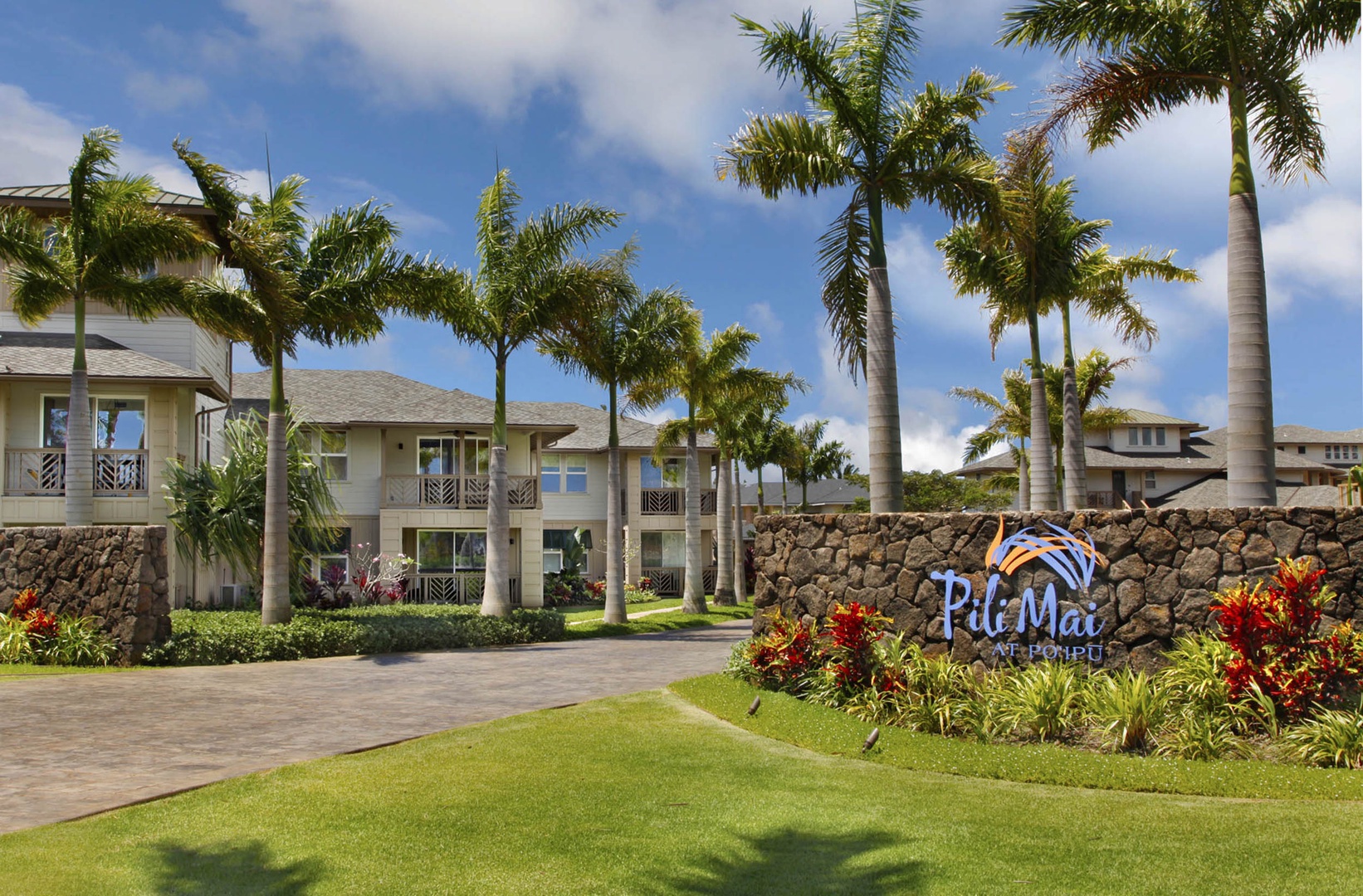 Koloa Vacation Rentals, Pili Mai 6J - Tropical resort entrance with swaying palms and lush landscaping welcomes guests to island paradise.
