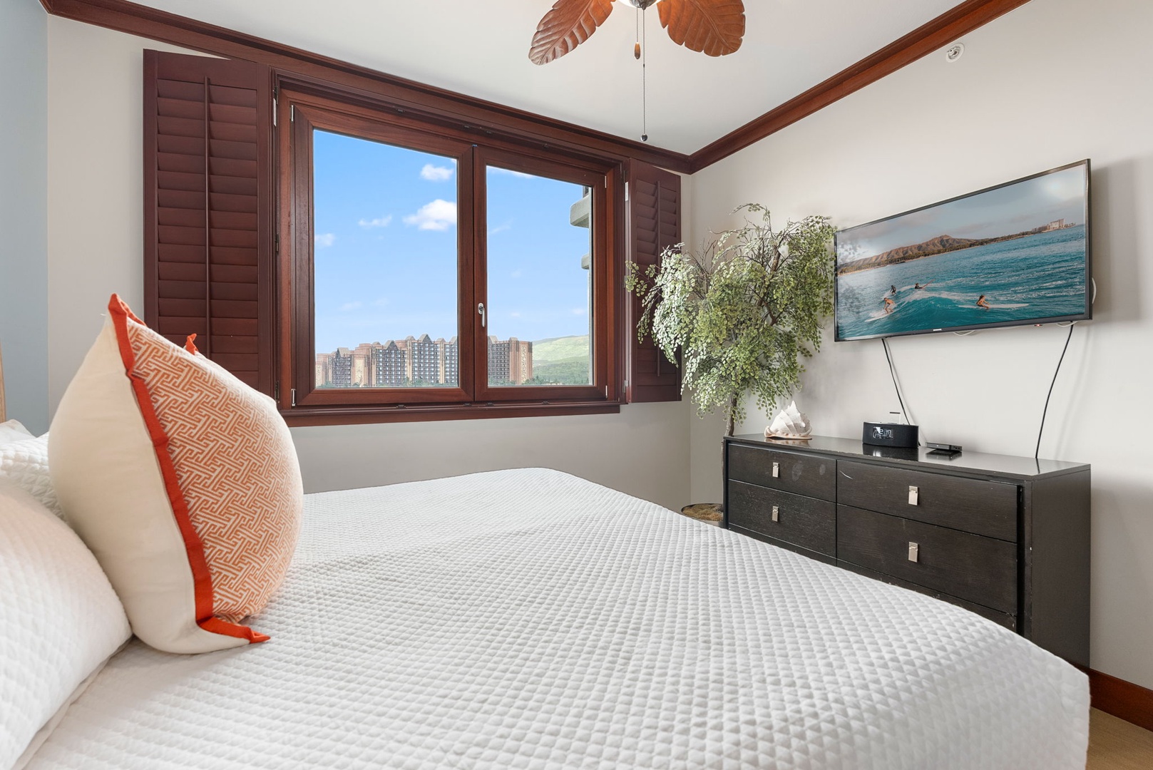 Kapolei Vacation Rentals, Ko Olina Beach Villas B604 - Relax in your serene bedroom with warm wood accents, tropical ceiling fan, and peaceful city views through shuttered windows.