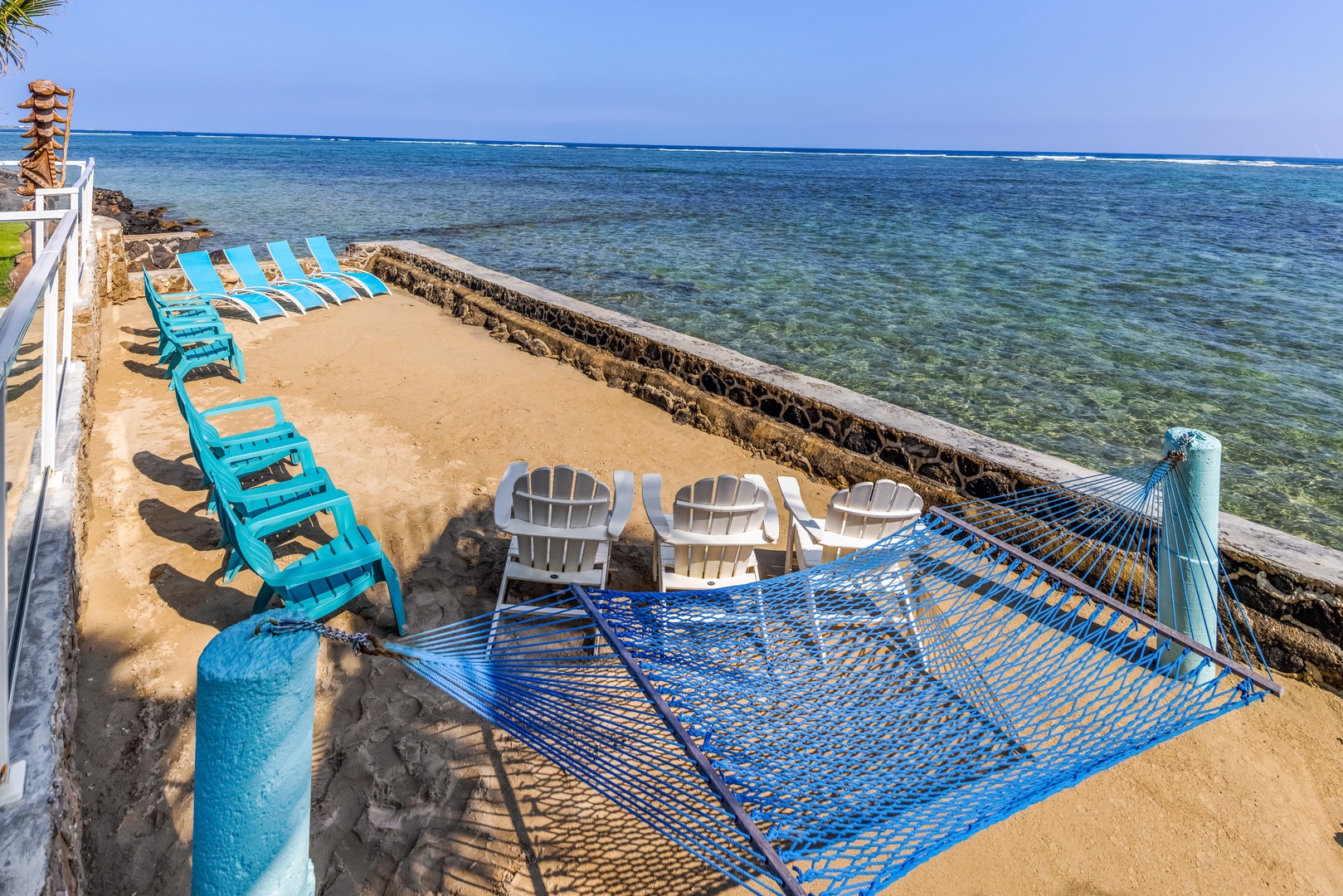 Hauula Vacation Rentals, Private Beach Paradise - A hammock and chairs at the water's edge, reef stretching out just beyond the wall.