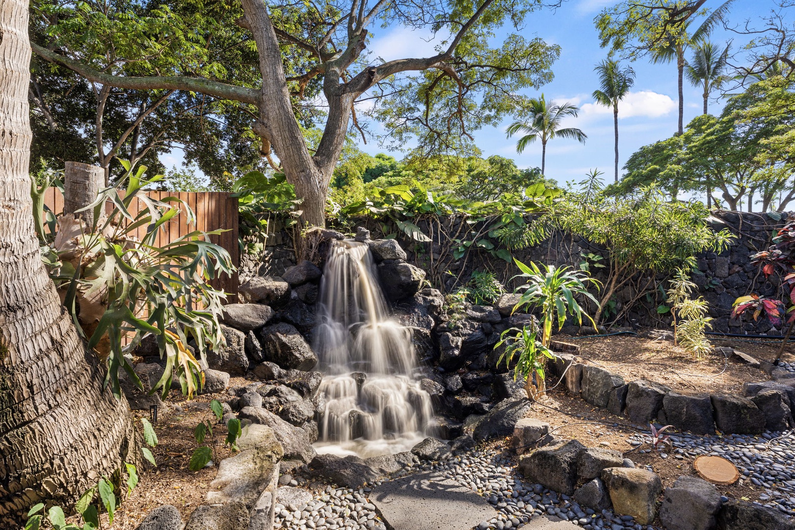 Kailua-Kona Vacation Rentals, Hahalua Bay Villa - Listen to the soothing cascade as you unwind in your private tropical oasis, surrounded by lush palms and natural stone.