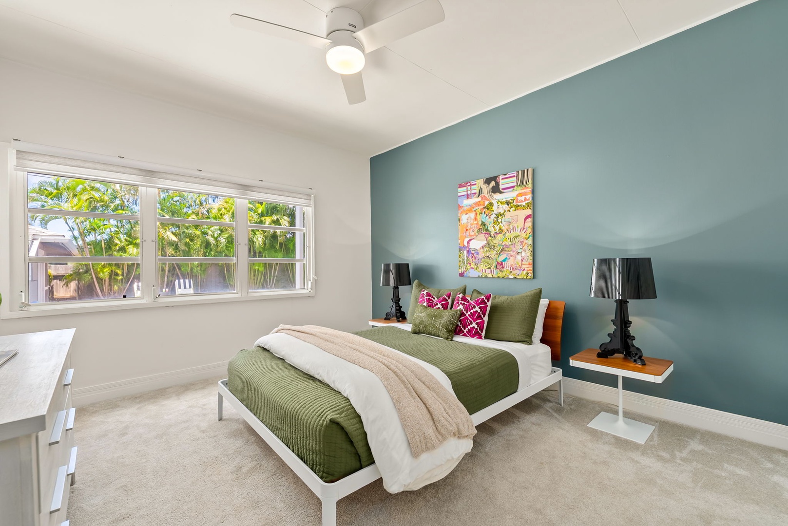 Honolulu Vacation Rentals, Ho'okipa Villa - Unwind in your stylish bedroom featuring modern decor, a plush bed with accent pillows, soothing teal walls, a bright garden view, and a ceiling fan for your comfort.
