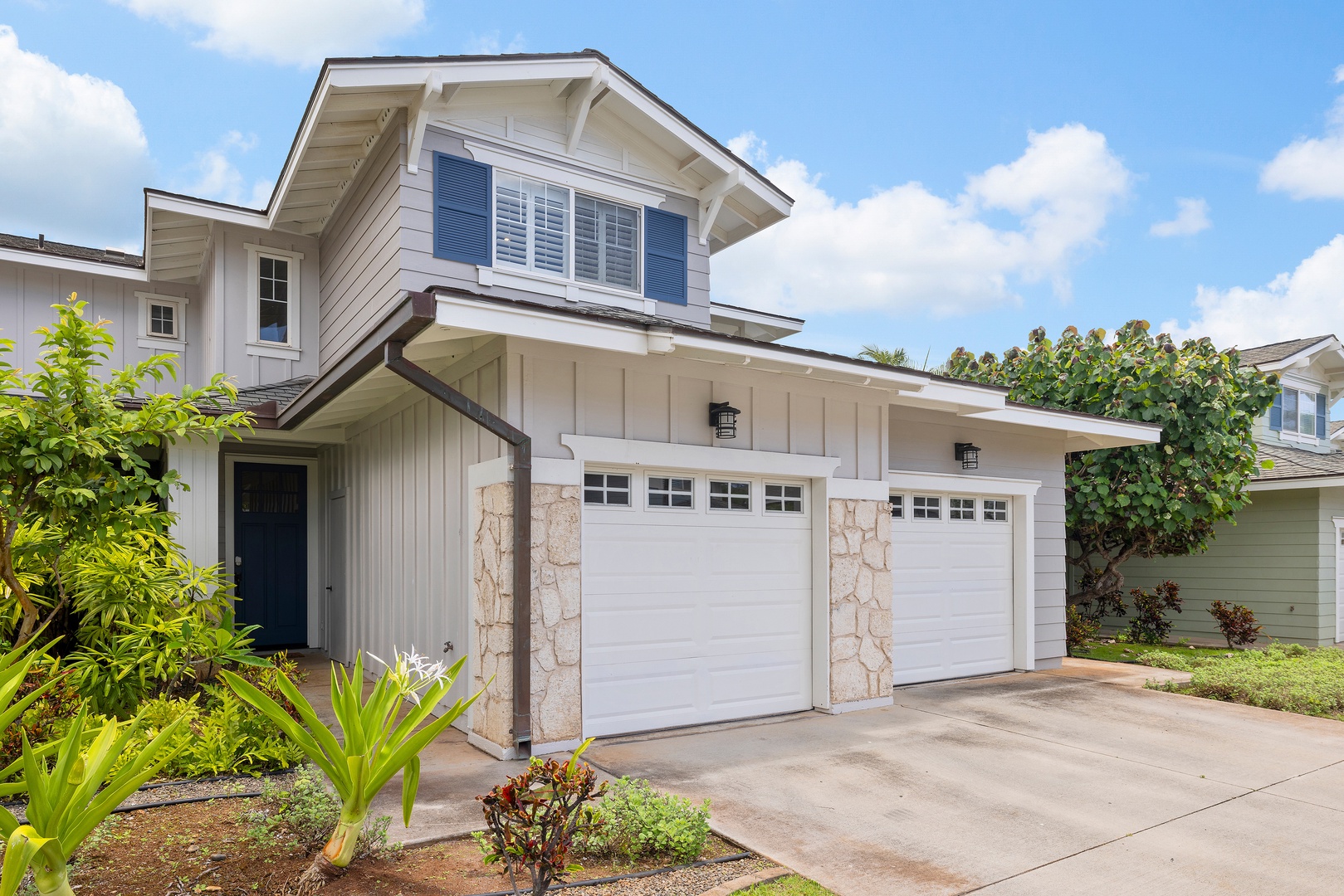 Kapolei Vacation Rentals, Ko Olina Kai 1105E - Charming property exterior with blue shutters and white siding, set in a lush residential neighborhood. The two-car garage and covered entryway welcome you to this coastal-style home.