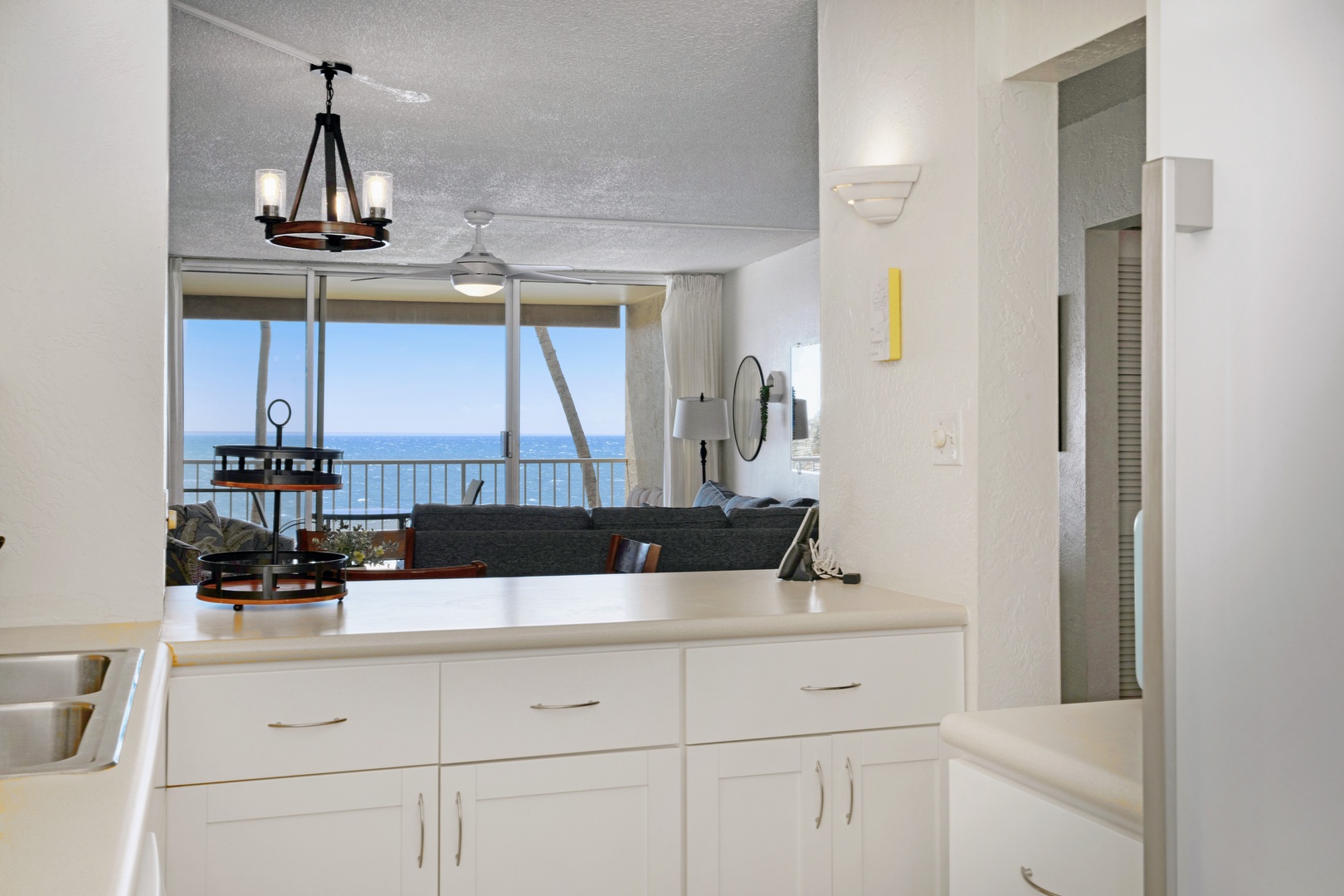 Kihei Vacation Rentals, Menehune Shores 316 - The pass-through counter frames the sectional and the ocean beyond it in one long sightline.