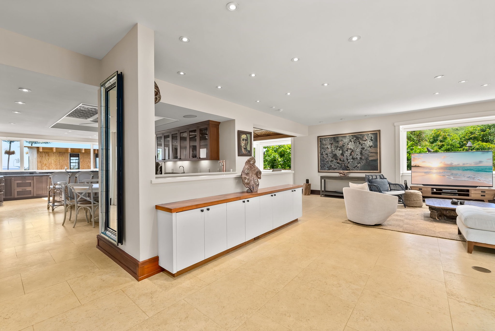 Kailua Vacation Rentals, Leaf House - Step into your open-plan haven where the kitchen flows seamlessly into the living area, bathed in natural light through floor-to-ceiling windows that frame a sparkling pool and lush greenery beyond.