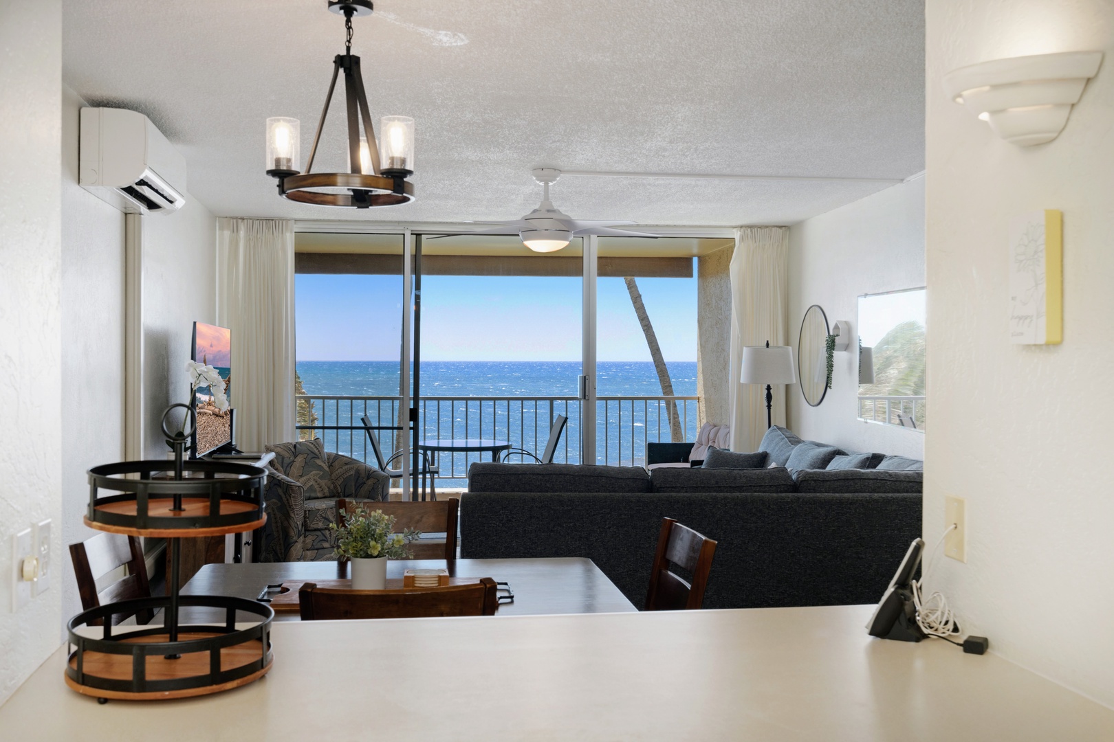Kihei Vacation Rentals, Menehune Shores 316 - A wood-ring chandelier hangs between the dining table and a living room that opens straight to the water.