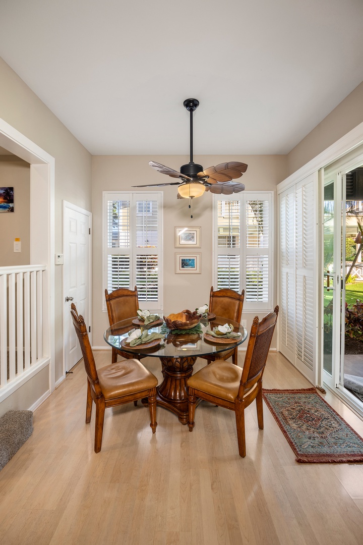 Your elegant dining space features a glass-topped table perfect for intimate meals, surrounded by comfortable leather chairs beneath a gentle ceiling fan.