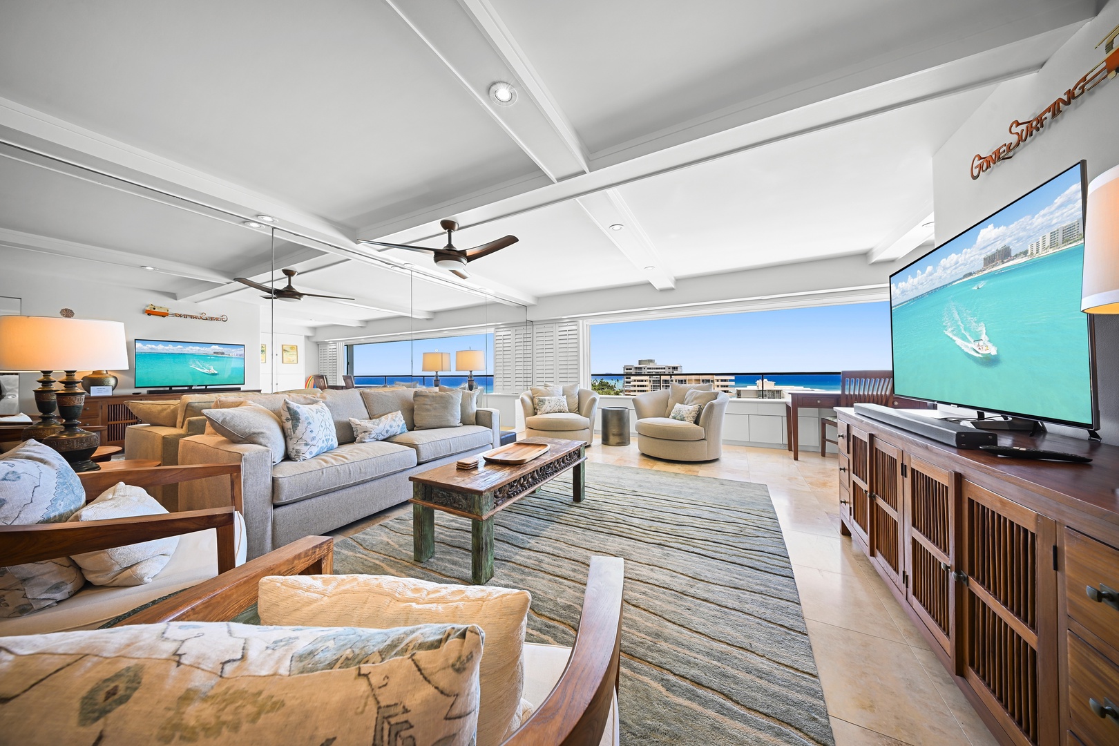 Honolulu Vacation Rentals, Kaimana Shores Getaway - Relax in the bright open-concept living area, where comfortable seating, coastal décor, and partial ocean views create a welcoming island retreat.