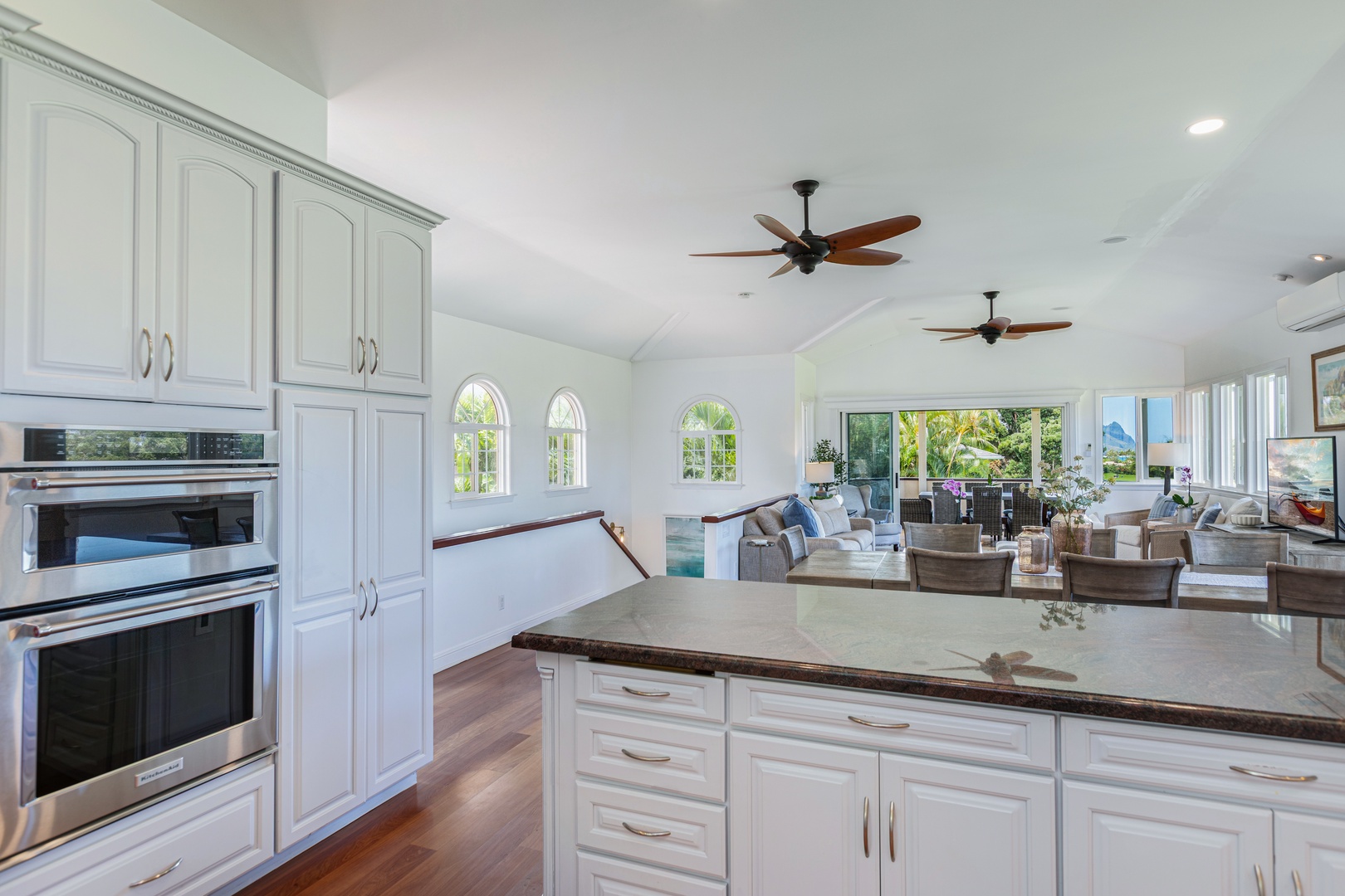 Princeville Vacation Rentals, Ohana Kamalani - Gourmet kitchen with white cabinetry and wood floors, blending modern style with island charm and functionality.