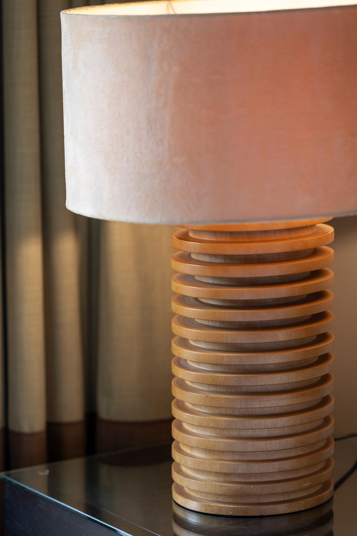 A sculptural wooden table lamp with a soft-glow shade adds warm, ambient lighting to your room, creating a cozy atmosphere for evening relaxation.