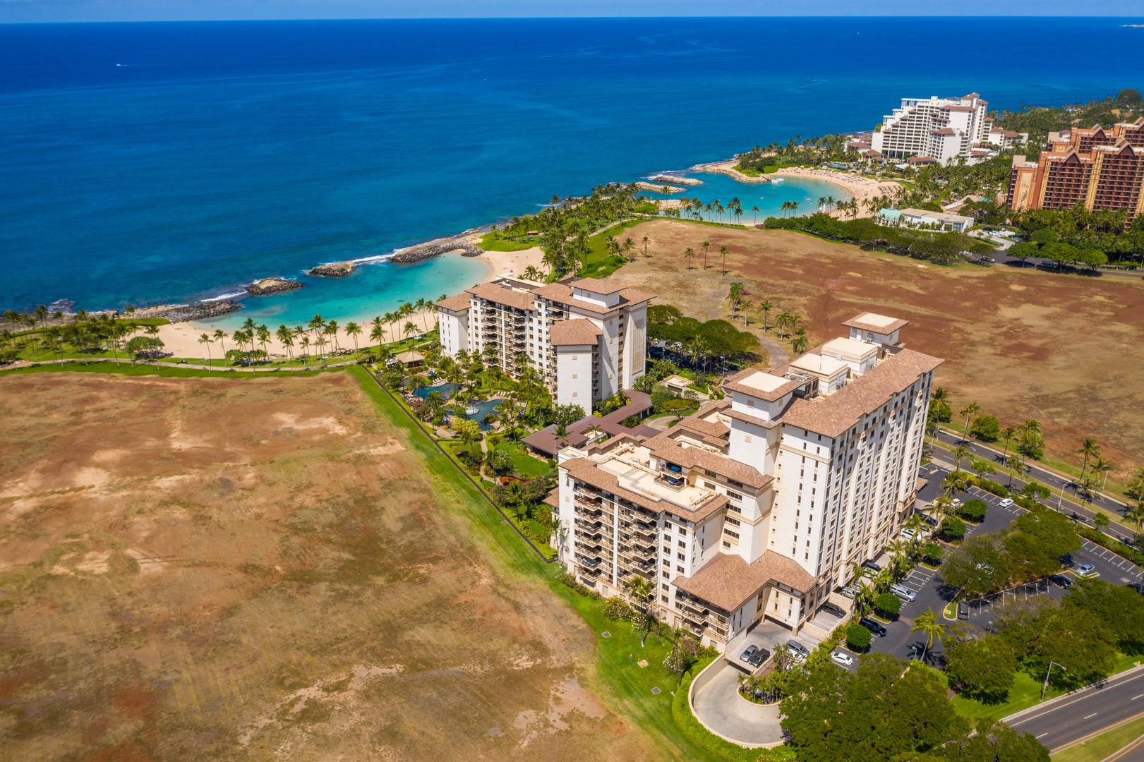 Lagoon water shades to open ocean where the coast bends past the villas.
