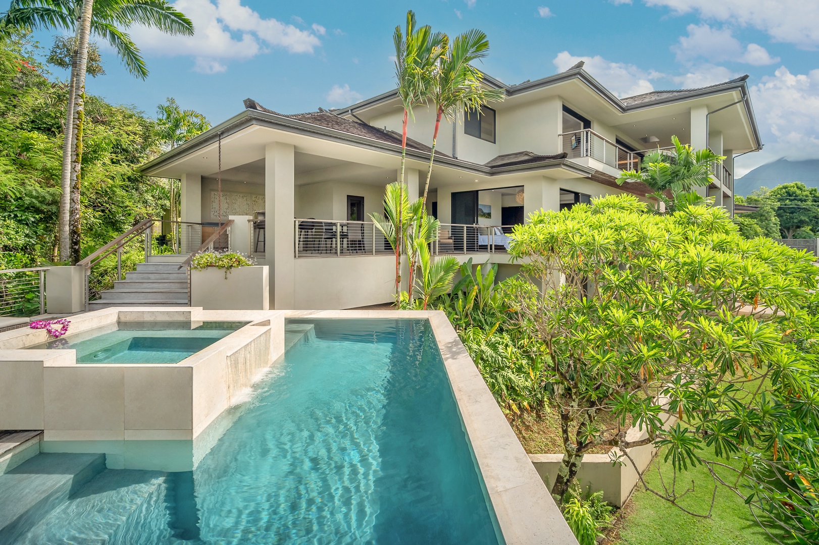 Princeville Vacation Rentals, Hanalei Plantation Villa - Modern pool area with seamless design connecting to the villa’s elegant exterior, surrounded by tropical greenery.