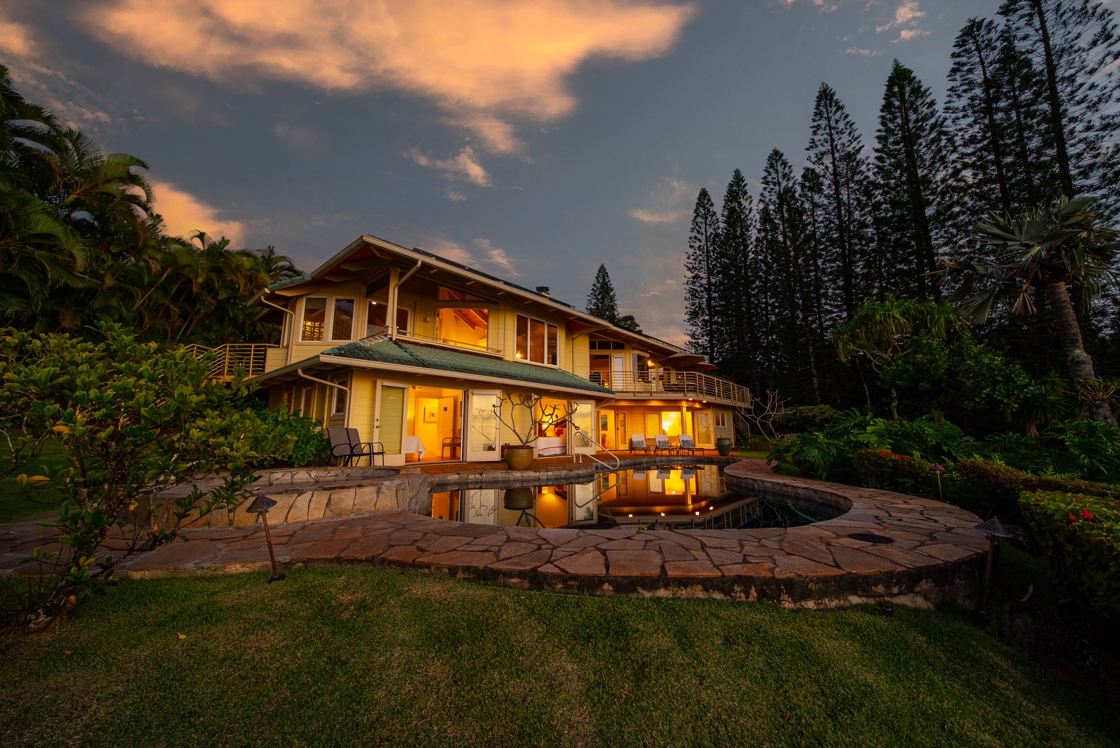 Haleiwa Vacation Rentals, Ka Hale Hau'oli - Tropical vacation home with swimming pool surrounded by lush gardens and towering palms during golden hour.