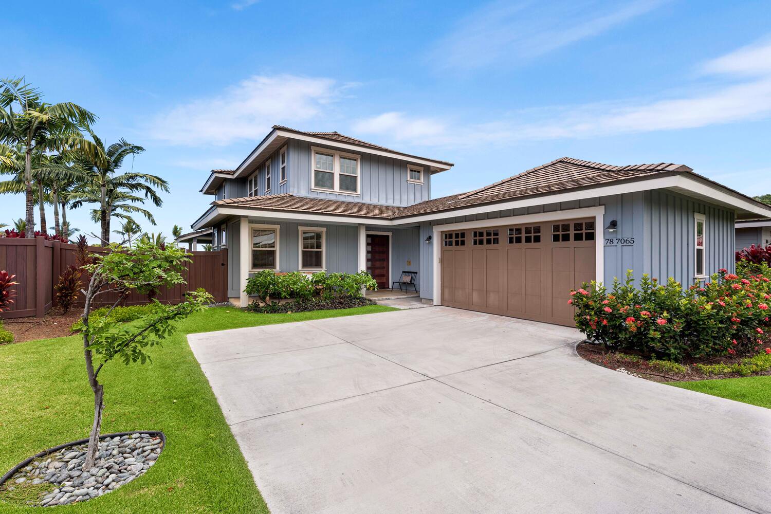 Kailua-Kona Vacation Rentals, Holua Kai #26 - A well-appointed two-story family home featuring a spacious driveway and manicured landscaping, under a clear blue sky.