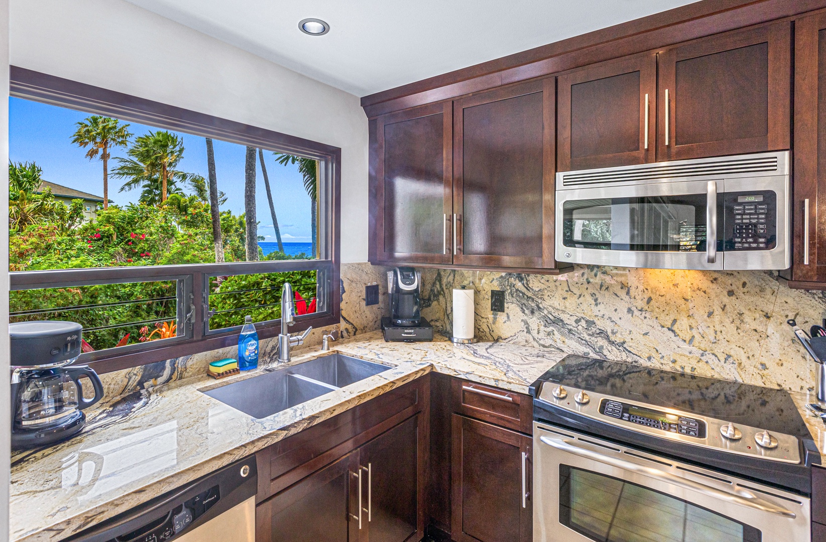 Kihei Vacation Rentals, Wailea Ekolu 1605 - The kitchen offers modern appliances and a window with a beautiful view of the ocean and palm trees, perfect for meal prep with a scenic backdrop.