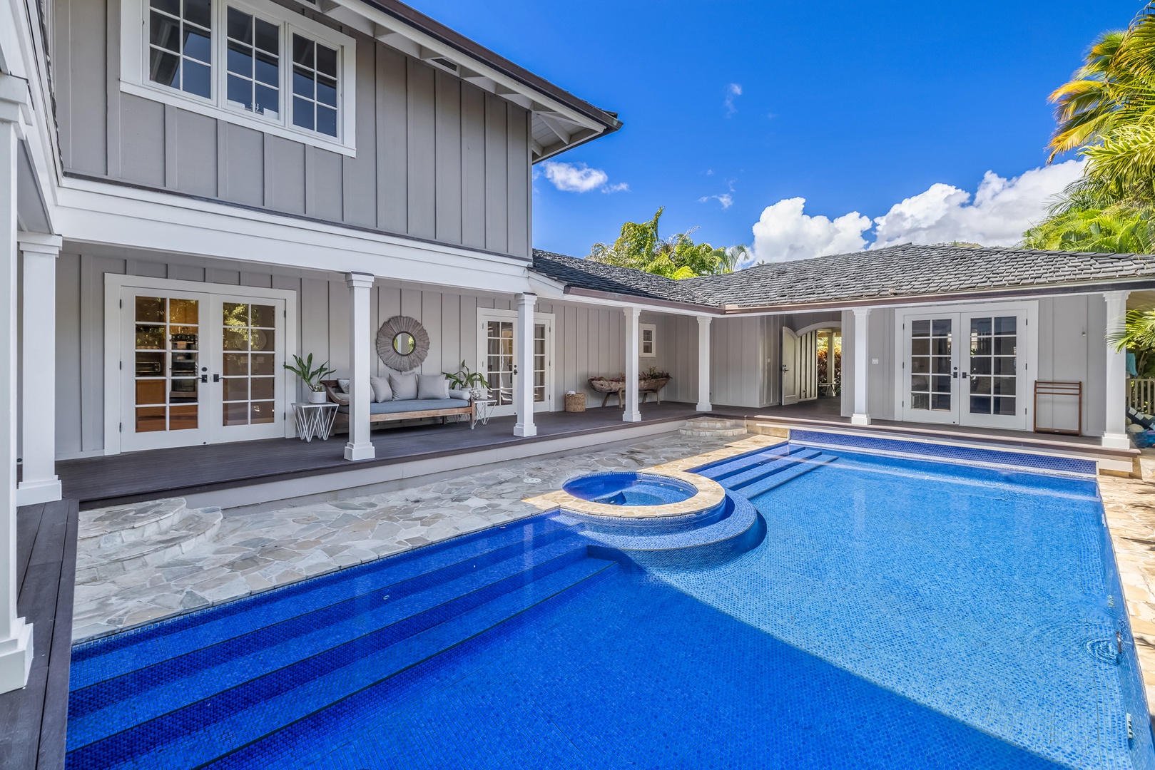 Honolulu Vacation Rentals, Moana Lani - Main House - Ease into the pool down the wide blue steps, with shaded lanai seating alongside.