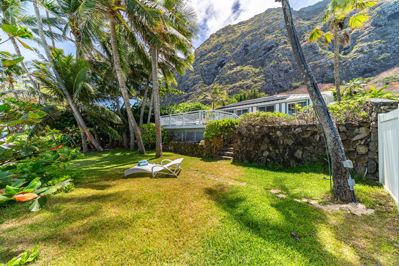 Waimanalo Vacation Rentals, Mana Kai at Waimanalo - Relax on the chaise lounge amidst a lush grassy expanse, with the luxurious home and majestic mountains framing the perfect backdrop.