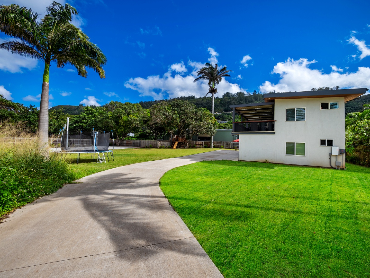 Haleiwa Vacation Rentals, Sunset Beach Island Retreat - A wide, curving driveway leads to this peaceful retreat, surrounded by lush greenery and stunning blue skies, perfect for enjoying the tranquility of the outdoors.