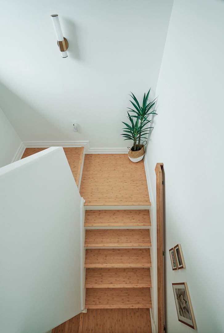 Princeville Vacation Rentals, Hale Kai - Ascend these bright wooden stairs to your private sanctuary, where modern pendant lighting and thoughtful plant details create a welcoming atmosphere.