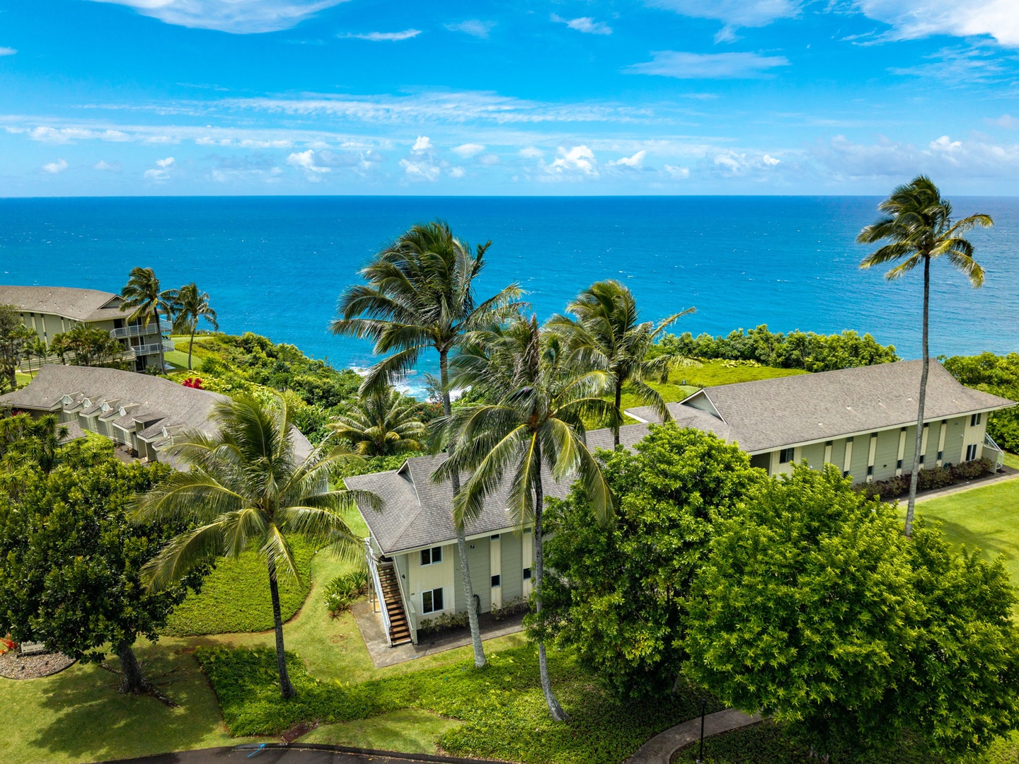 Princeville Vacation Rentals, Alii Kai 7201 - From above, low buildings sit in green lawns with the ocean at the edge.