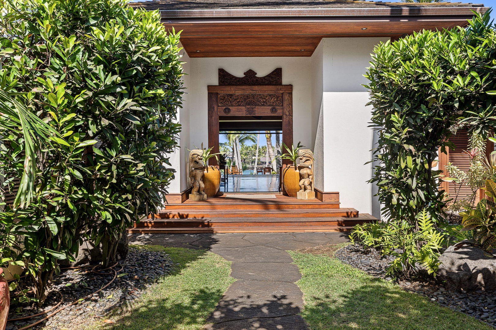 Kailua-Kona Vacation Rentals, Hahalua Bay Villa - An elegant entrance welcomes guests with carved wooden details, tropical landscaping, and traditional architectural charm.