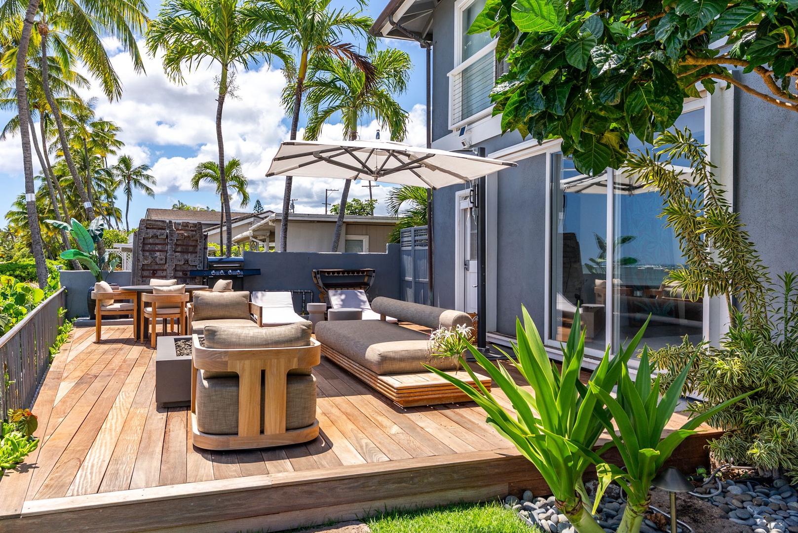 Honolulu Vacation Rentals, Wailupe Beachfront Getaway - Sunlit deck at Wailupe Beachfront Getaway with shaded lounge, dining table, and built-in BBQ.