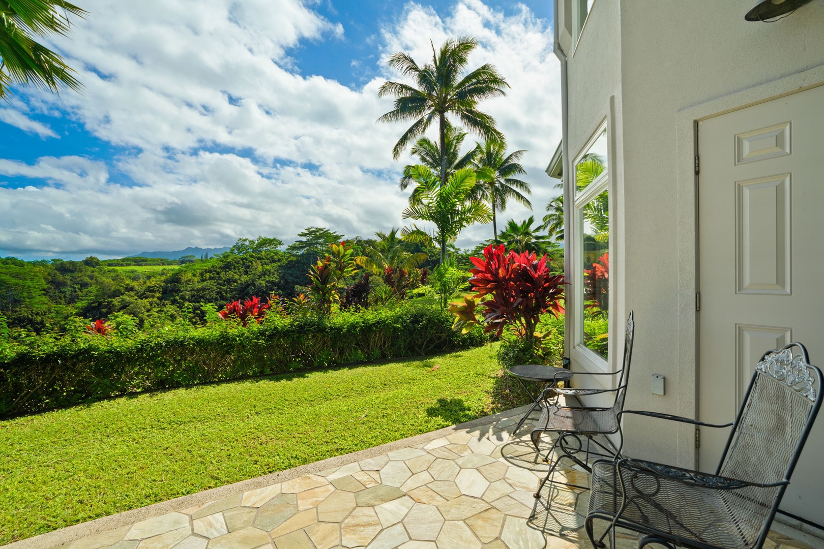 Princeville Vacation Rentals, Kaiulani #8 - Walk off the stone patio onto lawn edged with red ti and open green beyond.