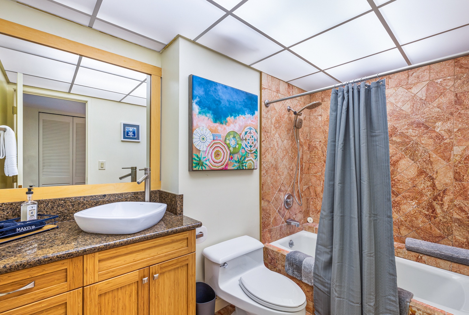 Lahaina Vacation Rentals, Kaanapali Shores 502 - This bathroom offers a peaceful retreat with its clean lines, bright artwork, and a spacious shower-tub combo. The granite vanity and bowl sink add a touch of elegance