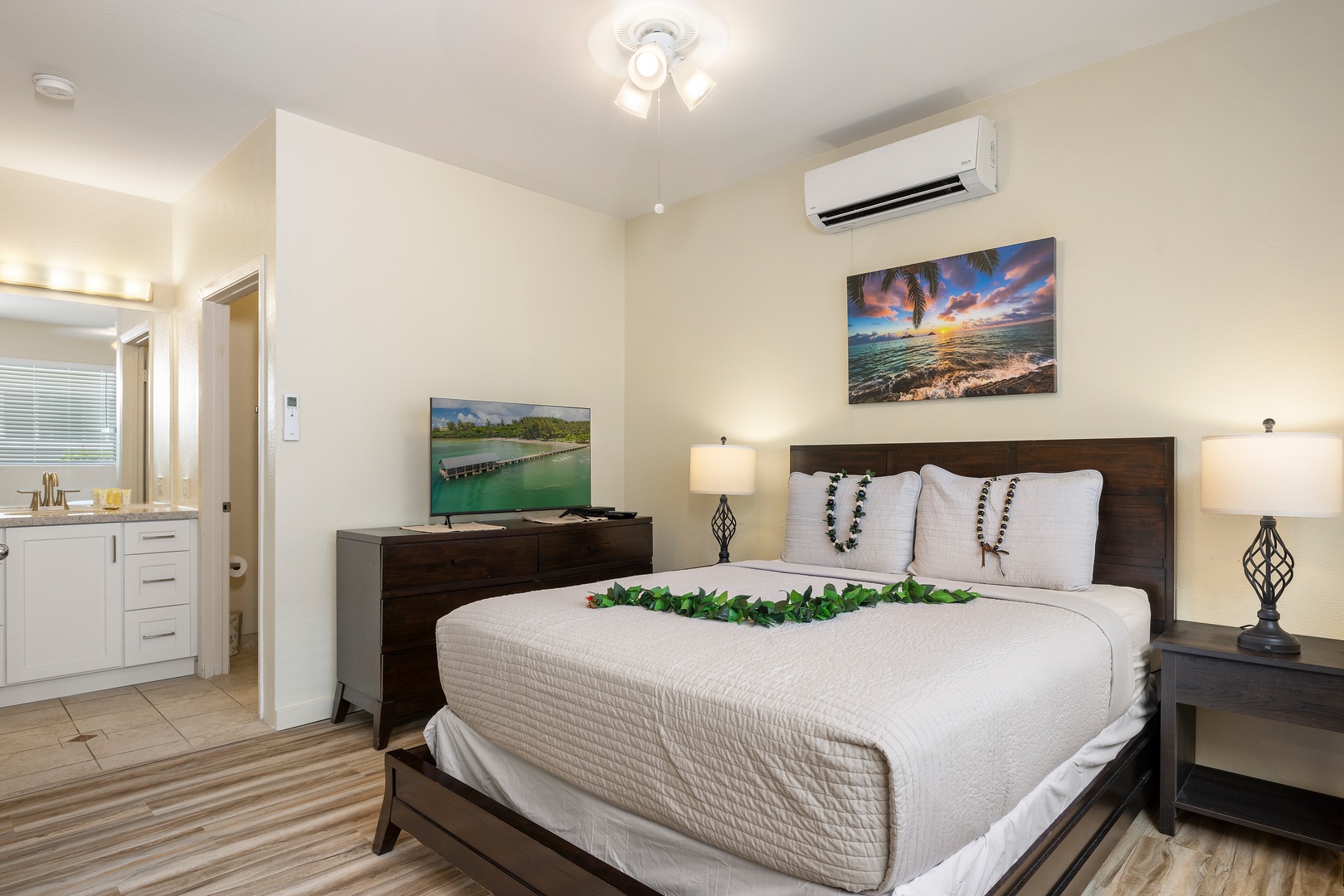 Unwind in your serene bedroom featuring a plush king bed, tropical artwork, and modern amenities for your perfect getaway.