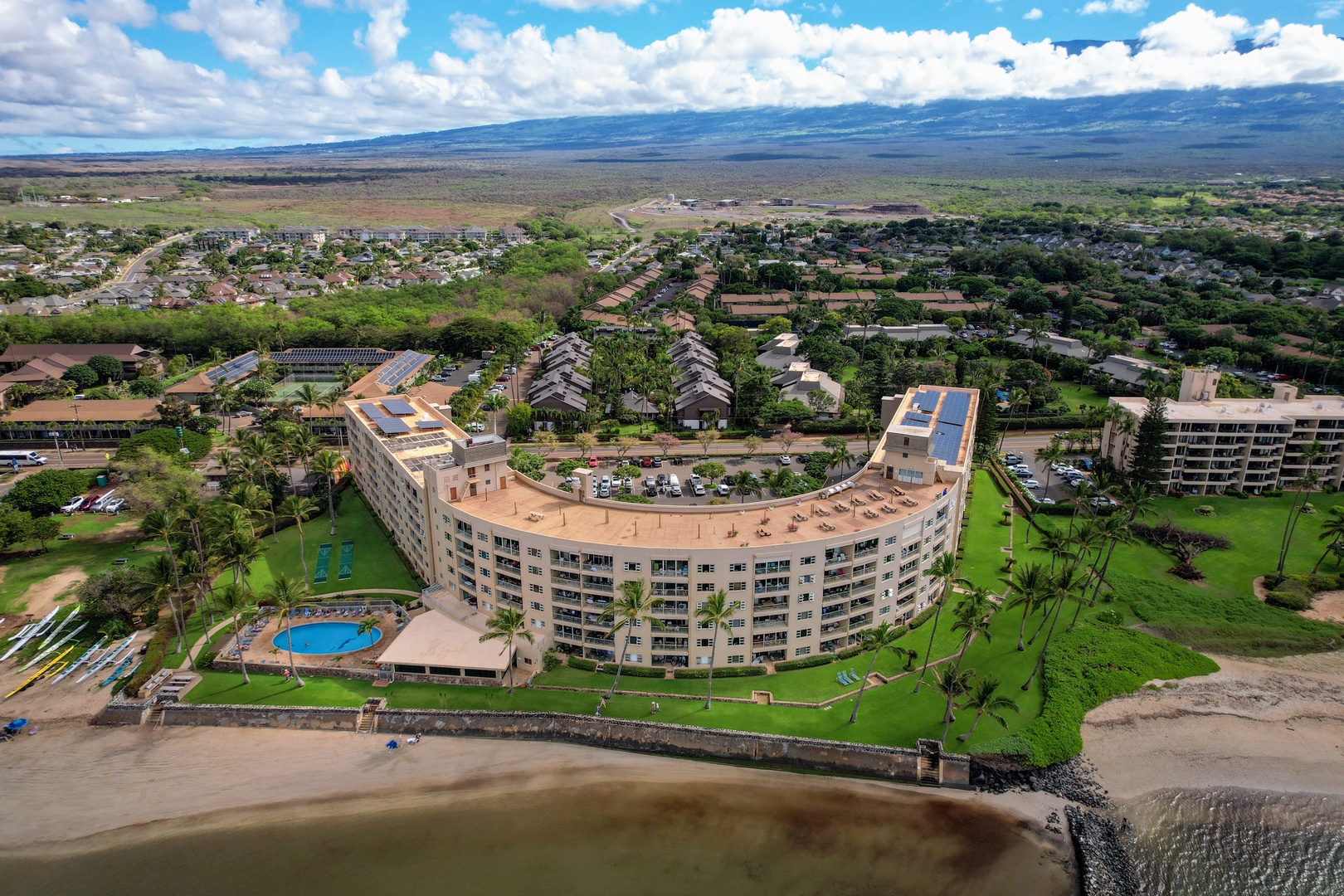 Kihei Vacation Rentals, Menehune Shores 316 - The building's crescent shape wraps a pool, a lawn, and a beach, all before the ocean takes over.