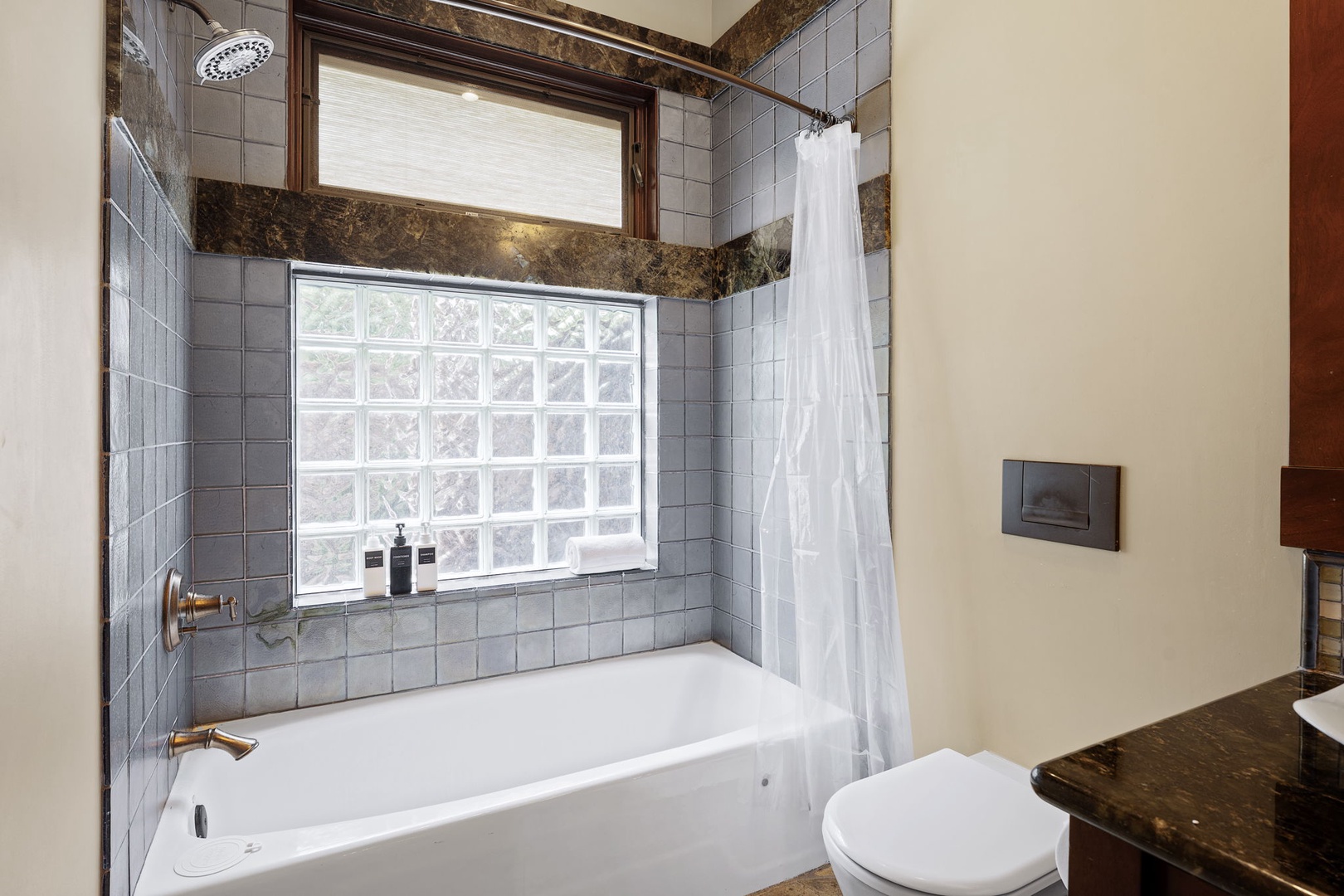 Kamuela Vacation Rentals, Hale Konane - Inviting bathroom with a soaking tub and privacy glass block window, perfect for relaxing after a beach day.