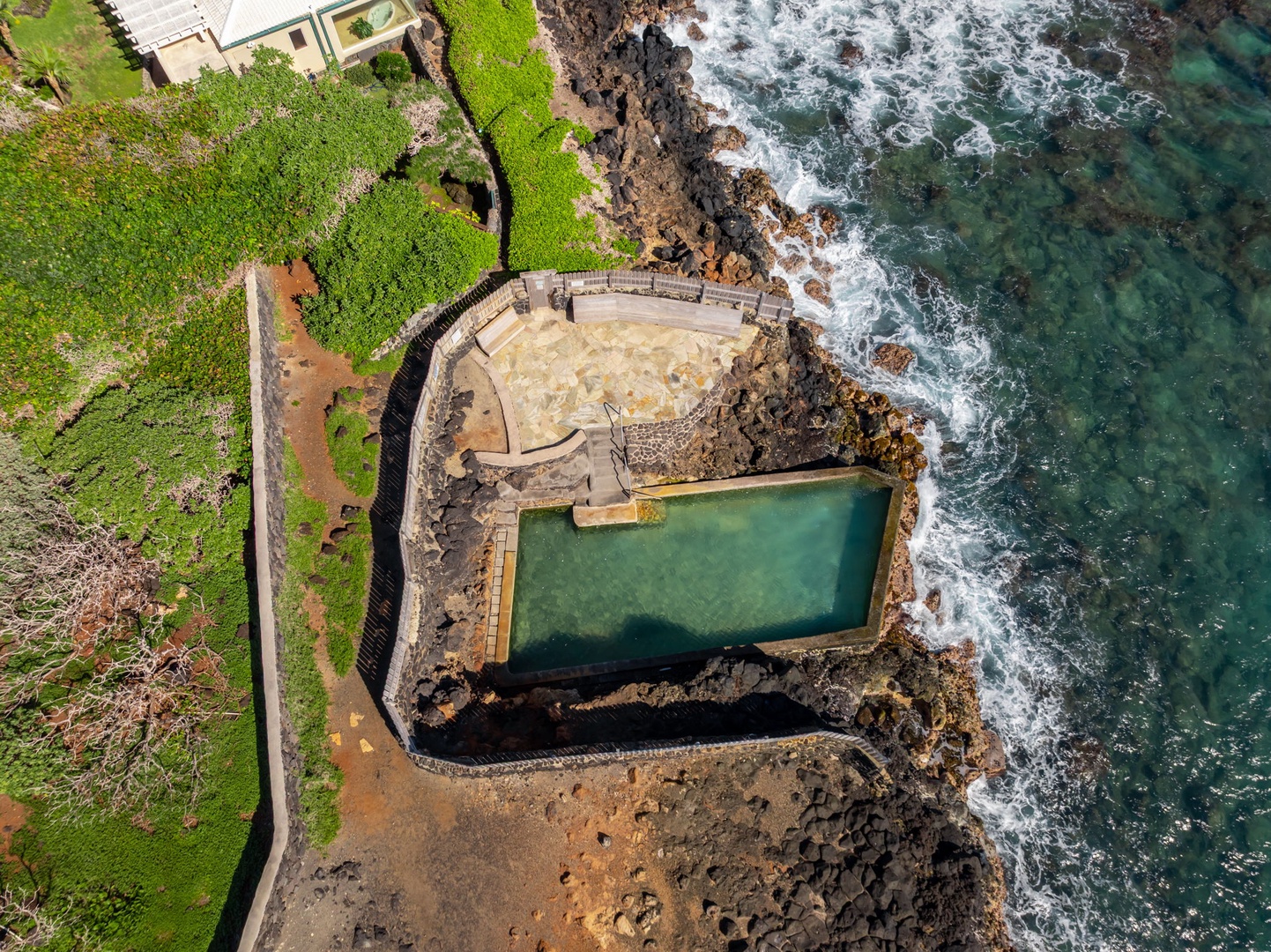 Honolulu Vacation Rentals, Black Point Ocean Villa - Aerial view captures stunning oceanfront natural pools carved into volcanic rock, surrounded by lush green landscape.