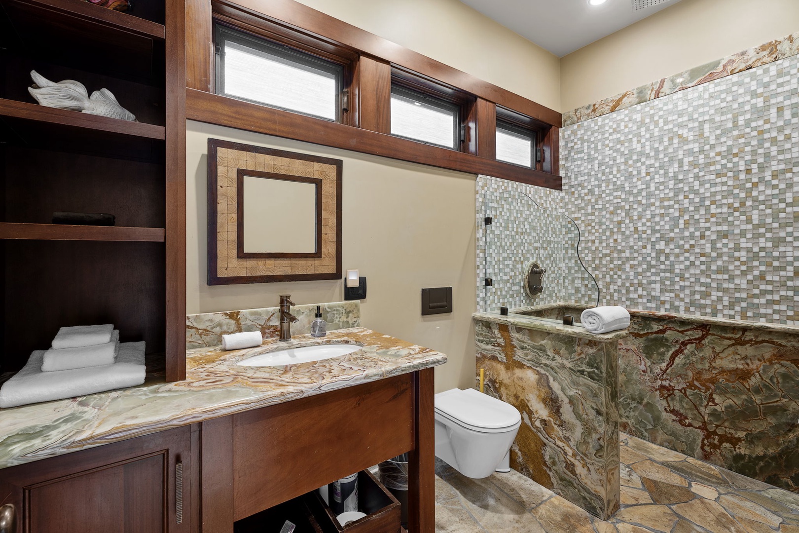 Kamuela Vacation Rentals, Hale Konane - Beautifully appointed bathroom with wood cabinetry and textured stonework for a warm, spa-like vibe.