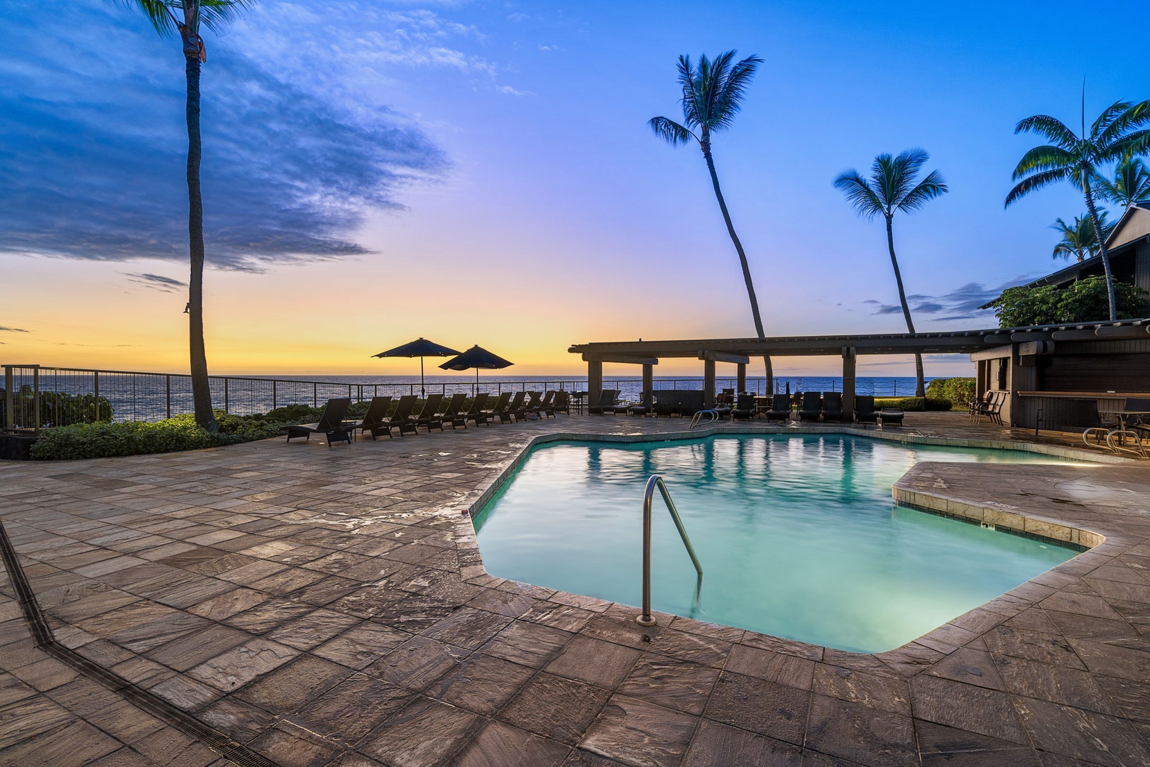 Kailua Kona Vacation Rentals, Kanaloa at Kona 1606 - The resort pool glows at dusk, palms leaning over the deck.