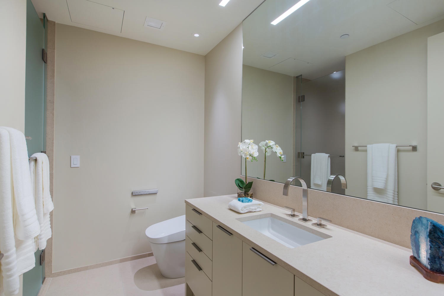 Honolulu Vacation Rentals, Park Lane Sunset Resort - Step into your pristine modern bathroom with sleek stone counters, fresh orchids, and plush towels awaiting your arrival.