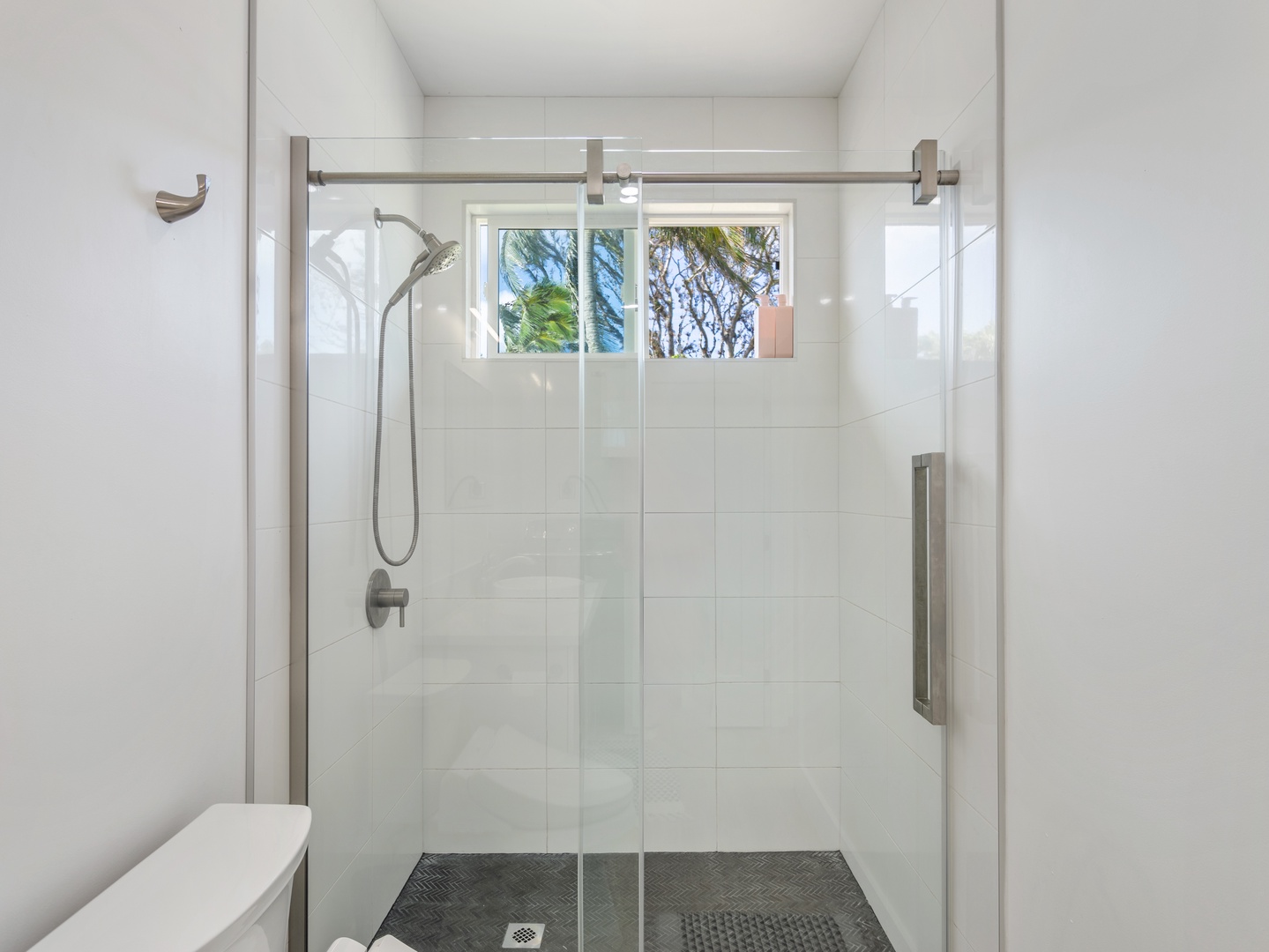 Haleiwa Vacation Rentals, Sunset Beach Island Retreat - This glass-enclosed shower features modern fixtures, a rainfall-style showerhead, and a window that lets in natural light, creating a bright and airy space to refresh after a long day.